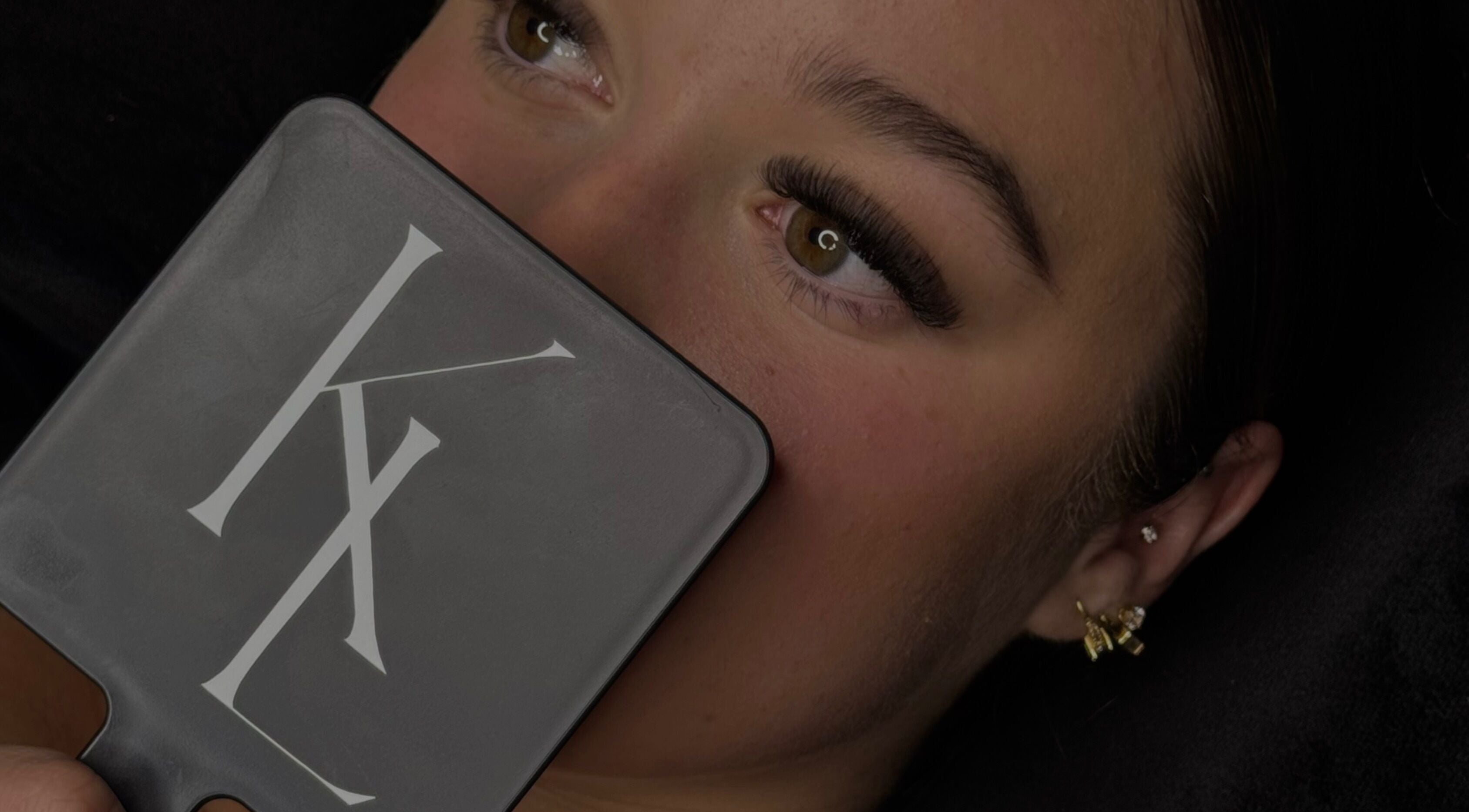 Close-up of woman admiring eyelash extensions in mirror at LASHES BY KL, Tahmoor, New South Wales, AU.
