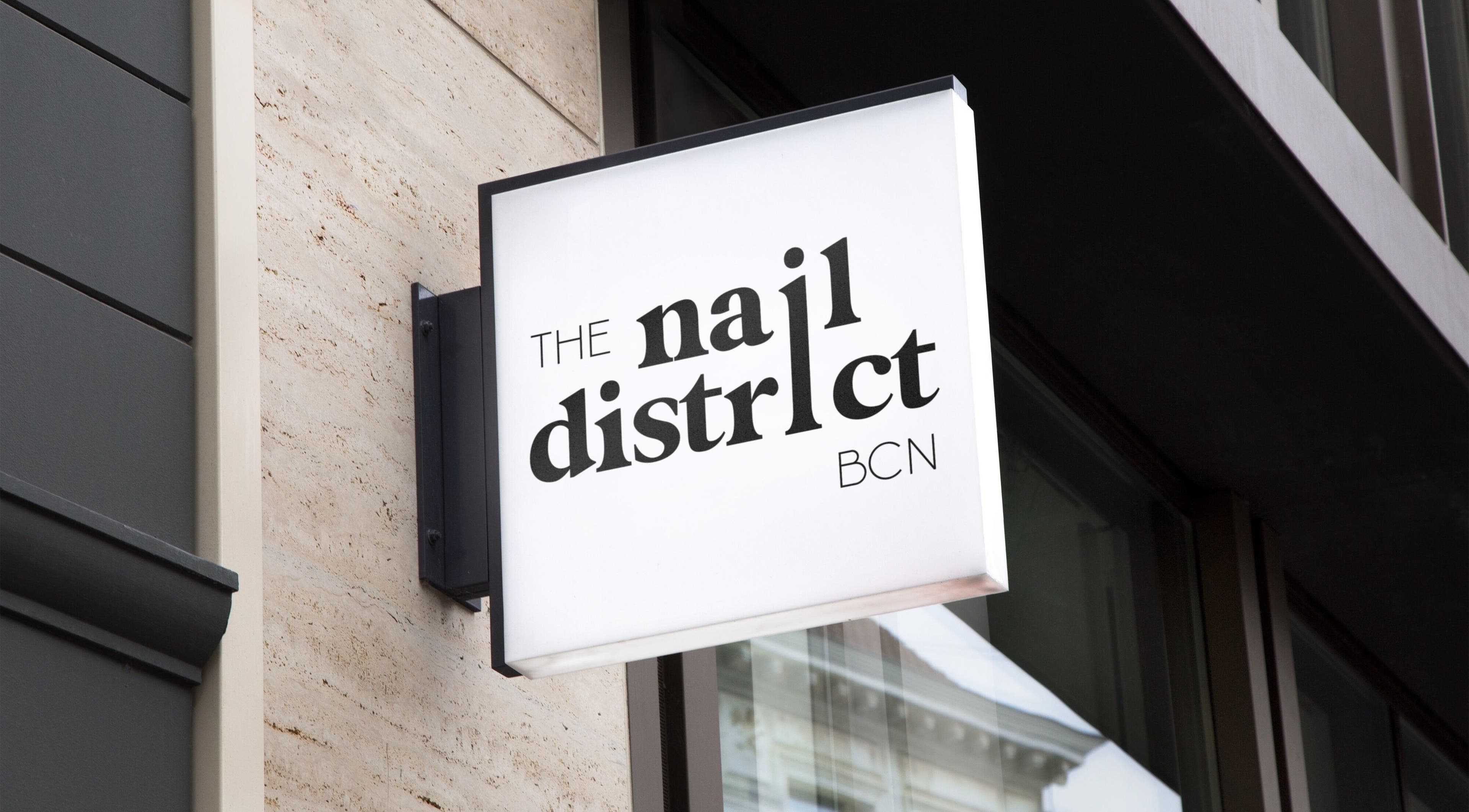 Letrero de The nail district BCN en Mérida, Extremadura, ES, destacando su moderna fachada.