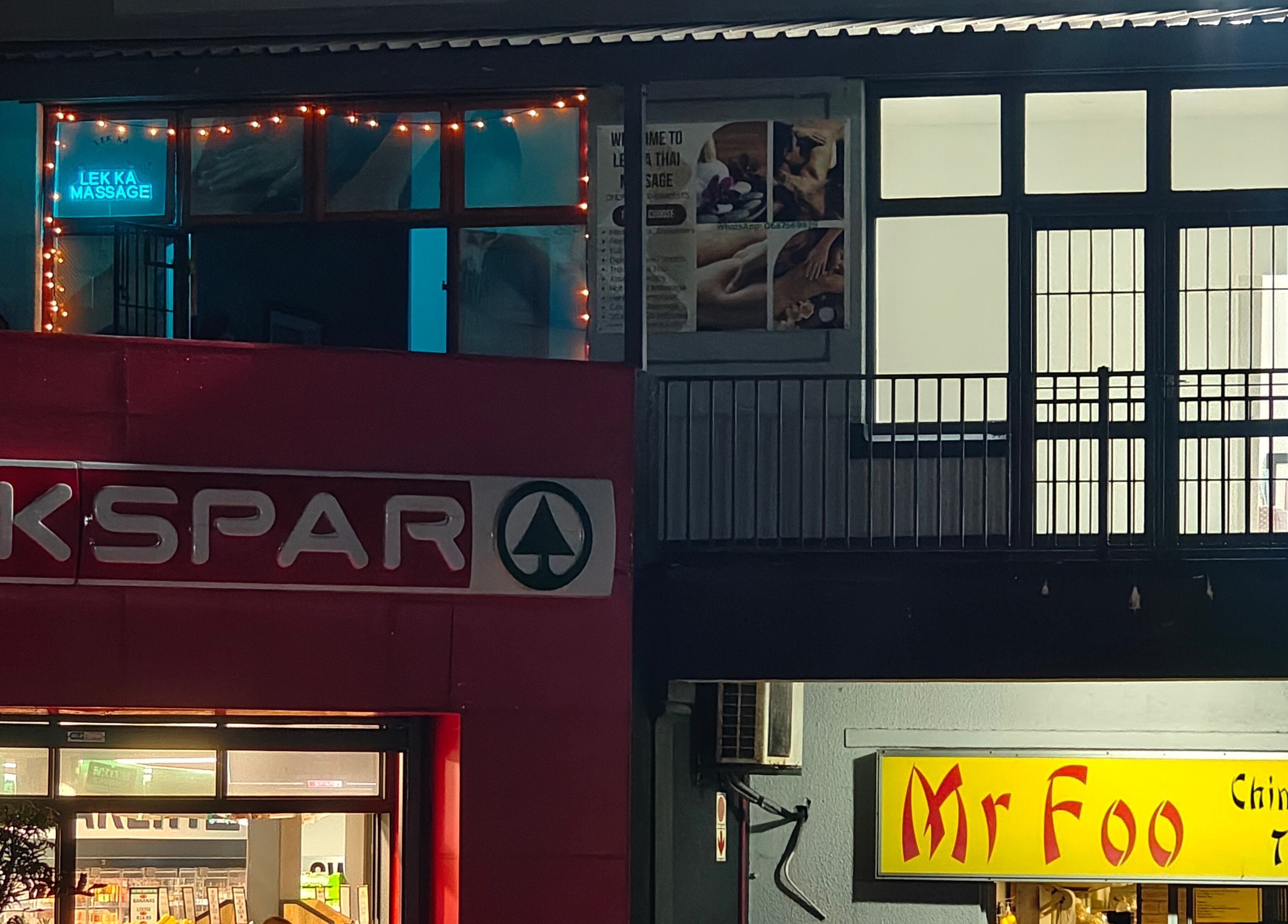 Lek Ka Thai Massage Studio's illuminated sign in Cape Town, Western Cape, ZA at night above shops.