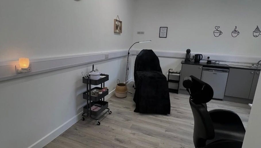 Cozy treatment room at AMP Beauty, Clay Cross, England, GB with a black-covered chair and warm lighting.