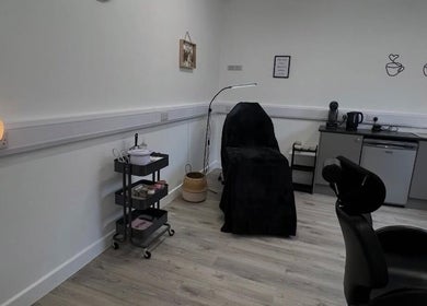Cozy treatment room at AMP Beauty, Clay Cross, England, GB with a black-covered chair and warm lighting.