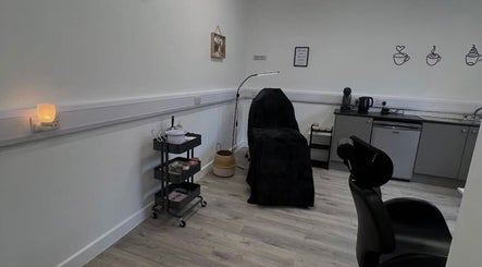 Cozy treatment room at AMP Beauty, Clay Cross, England, GB with a black-covered chair and warm lighting.