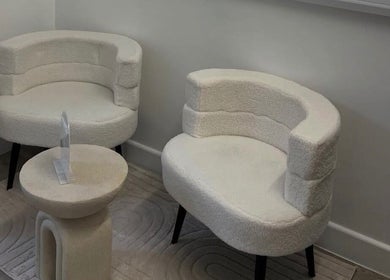Elegant seating area at AMP Beauty in Clay Cross, England, GB with plush white chairs and a stylish small table.