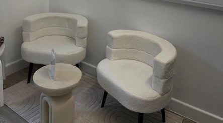 Elegant seating area at AMP Beauty in Clay Cross, England, GB with plush white chairs and a stylish small table.