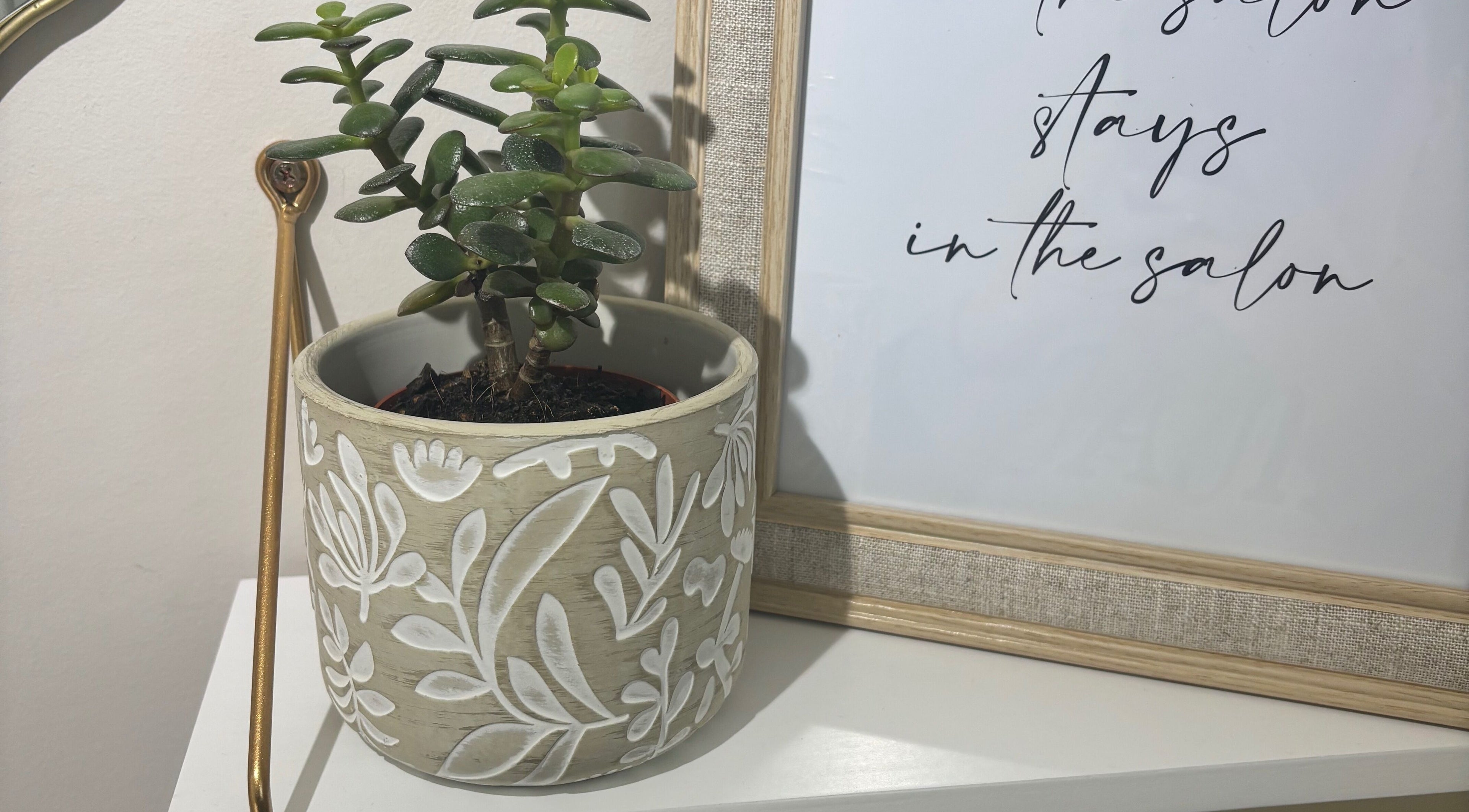Elegant plant and framed quote at Nails By Jade, Uxbridge, England, GB creating a tranquil atmosphere.