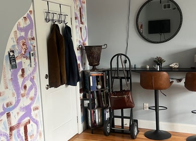Stylish corner at Careful Touch, Detroit, Michigan, US, featuring bar stools, a mirror, and unique wall art.