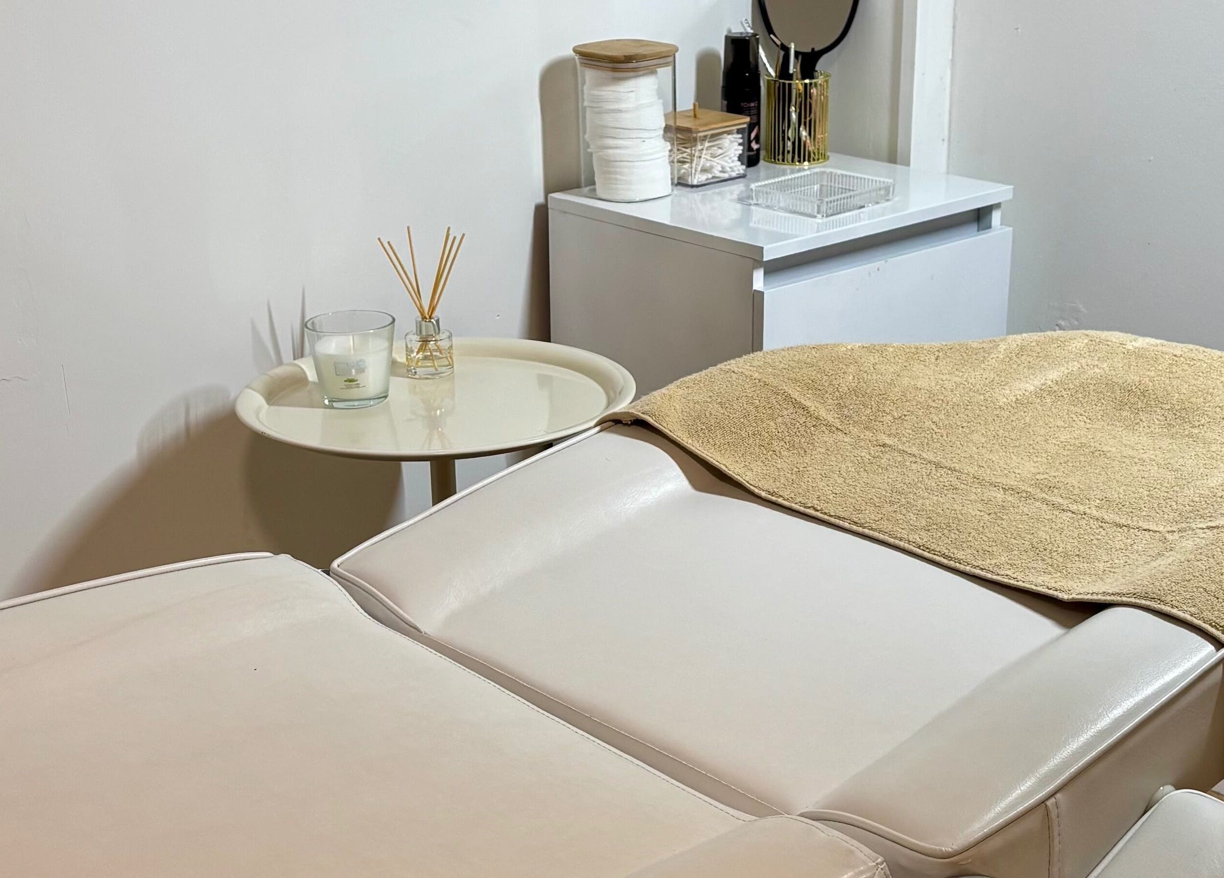 Cabina de tratamiento en Beautify, Bootle, England, GB, con mesa de masaje blanca y decoración relajante.