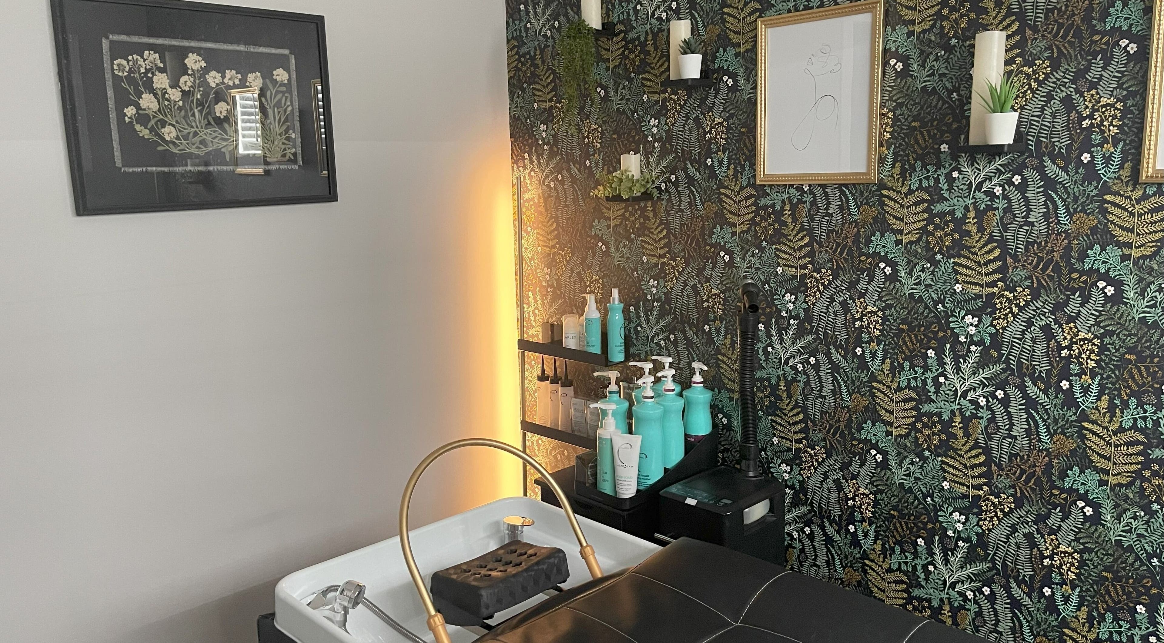 Washing station at The Collective Wellness Lounge, Lebanon, Indiana, US, with floral wallpaper and beauty products.