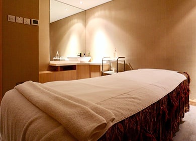 Relaxing treatment room at Yinyang Spa-Village Mall, Dubai, Dubai, AE featuring warm lighting and massage bed.