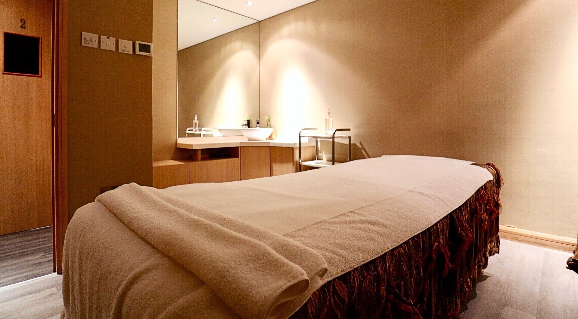 Relaxing treatment room at Yinyang Spa-Village Mall, Dubai, Dubai, AE featuring warm lighting and massage bed.