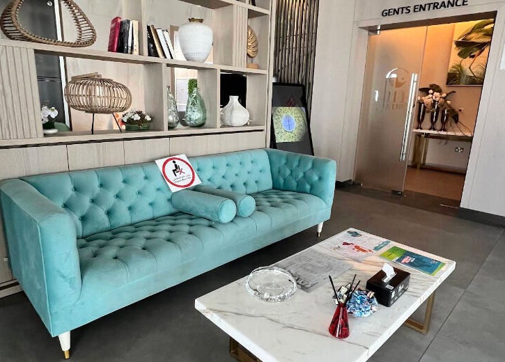 Relaxing lounge area at Yinyang Spa - Al Ferdous, Dubai, Dubai, AE, featuring a teal sofa and decorative items.