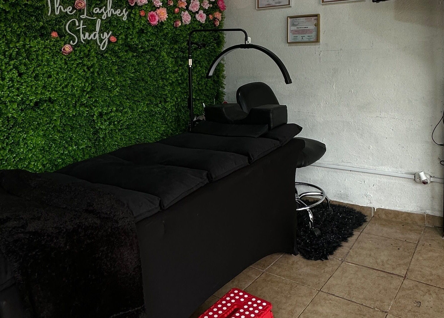 Espacio relajante en The Lashes Study, Monterosa, Heredia, CR, con camilla negra y decoraciones florales.
