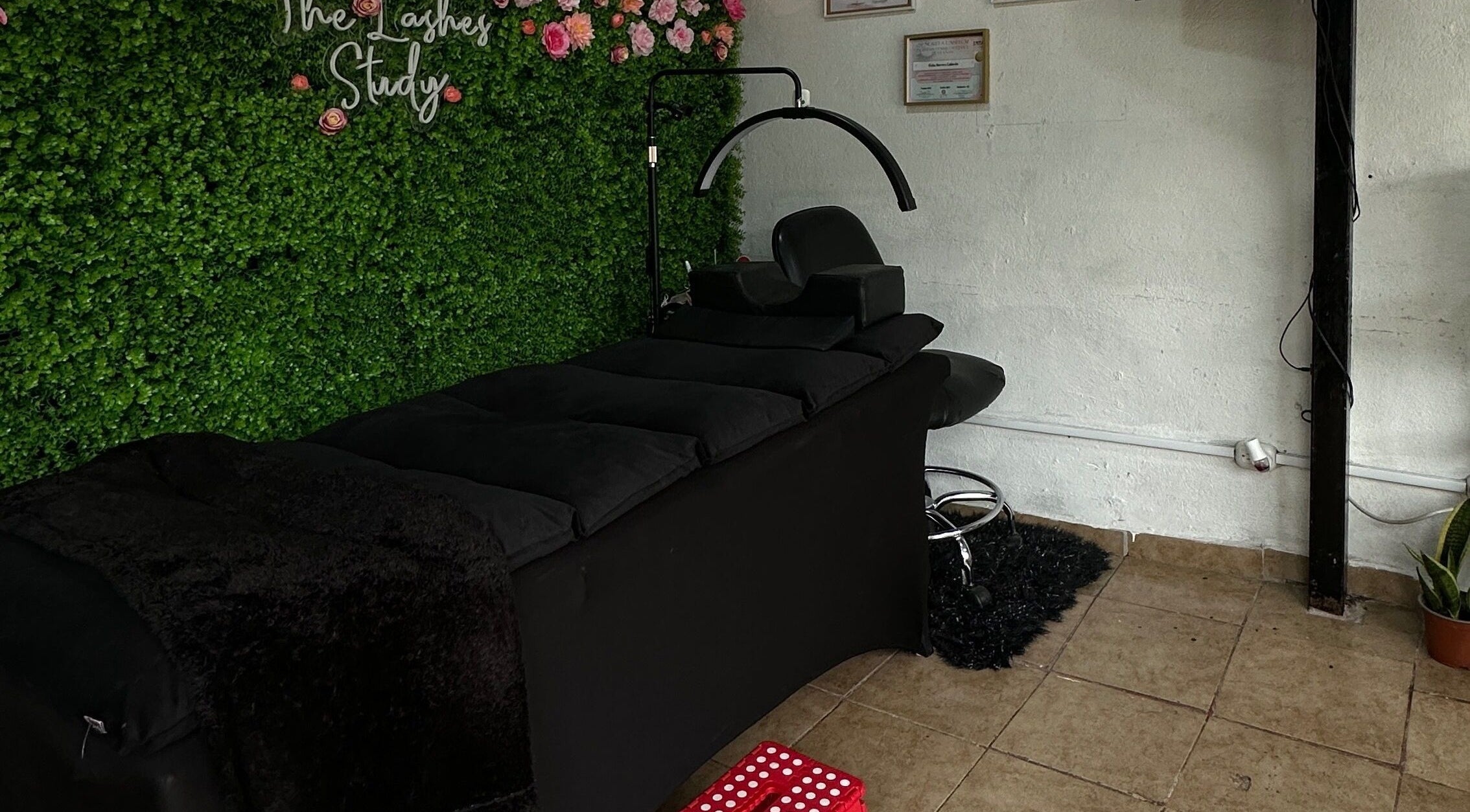 Espacio relajante en The Lashes Study, Monterosa, Heredia, CR, con camilla negra y decoraciones florales.