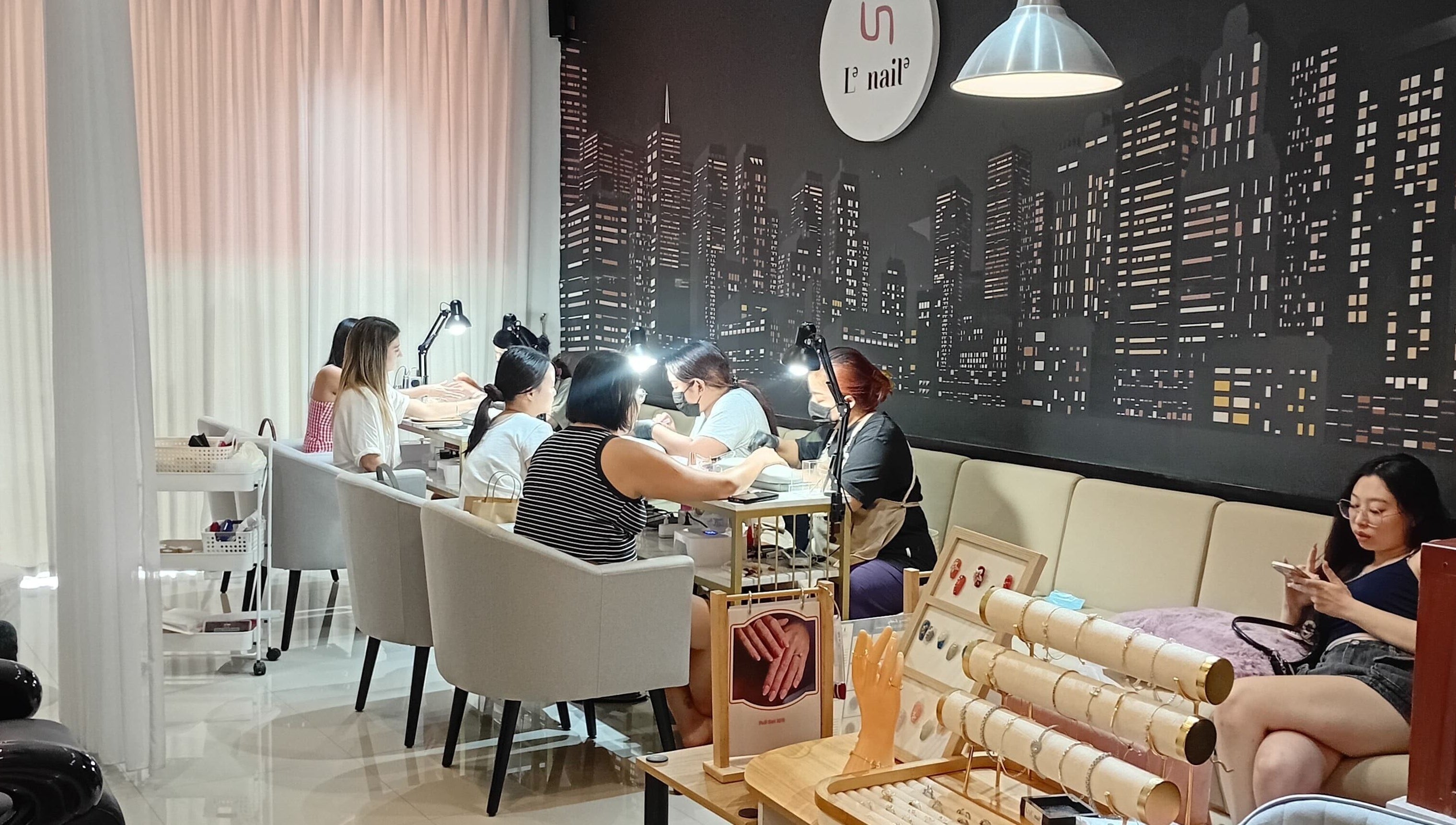 Clients enjoying nail services at Le Naile Beauty Studio, Bali, Bali, ID with a stylish cityscape backdrop.