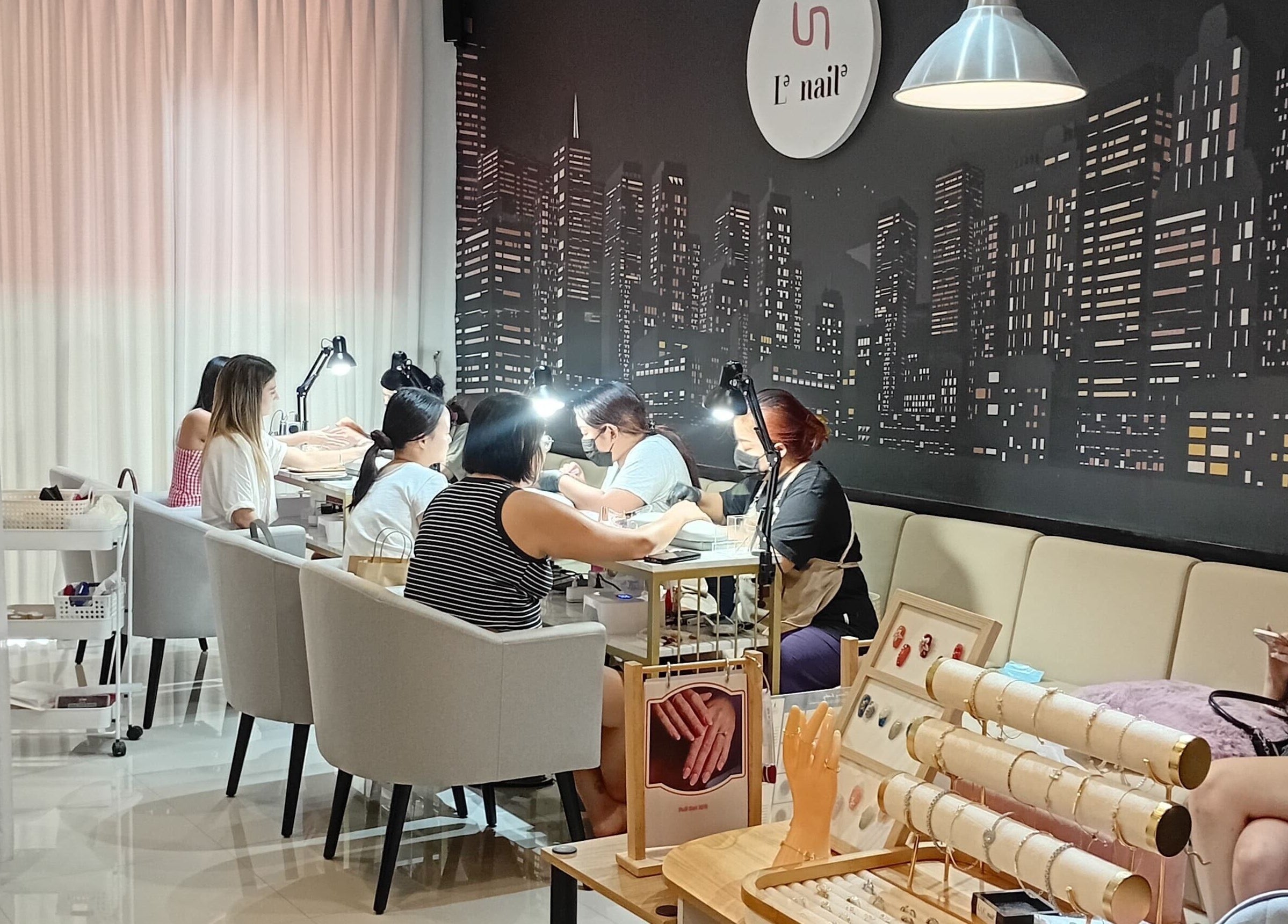 Clients enjoying nail services at Le Naile Beauty Studio, Bali, Bali, ID with a stylish cityscape backdrop.