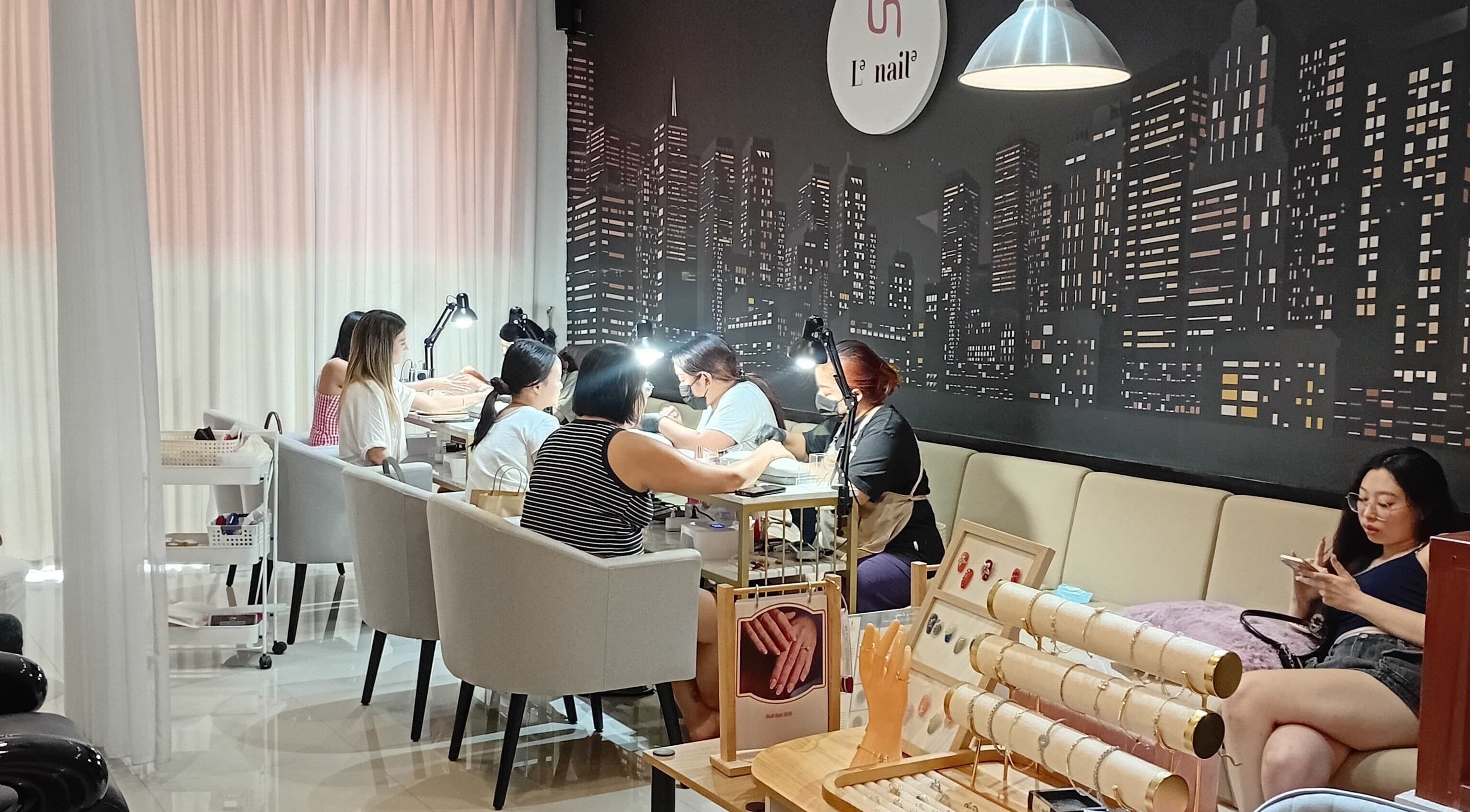Clients enjoying nail services at Le Naile Beauty Studio, Bali, Bali, ID with a stylish cityscape backdrop.