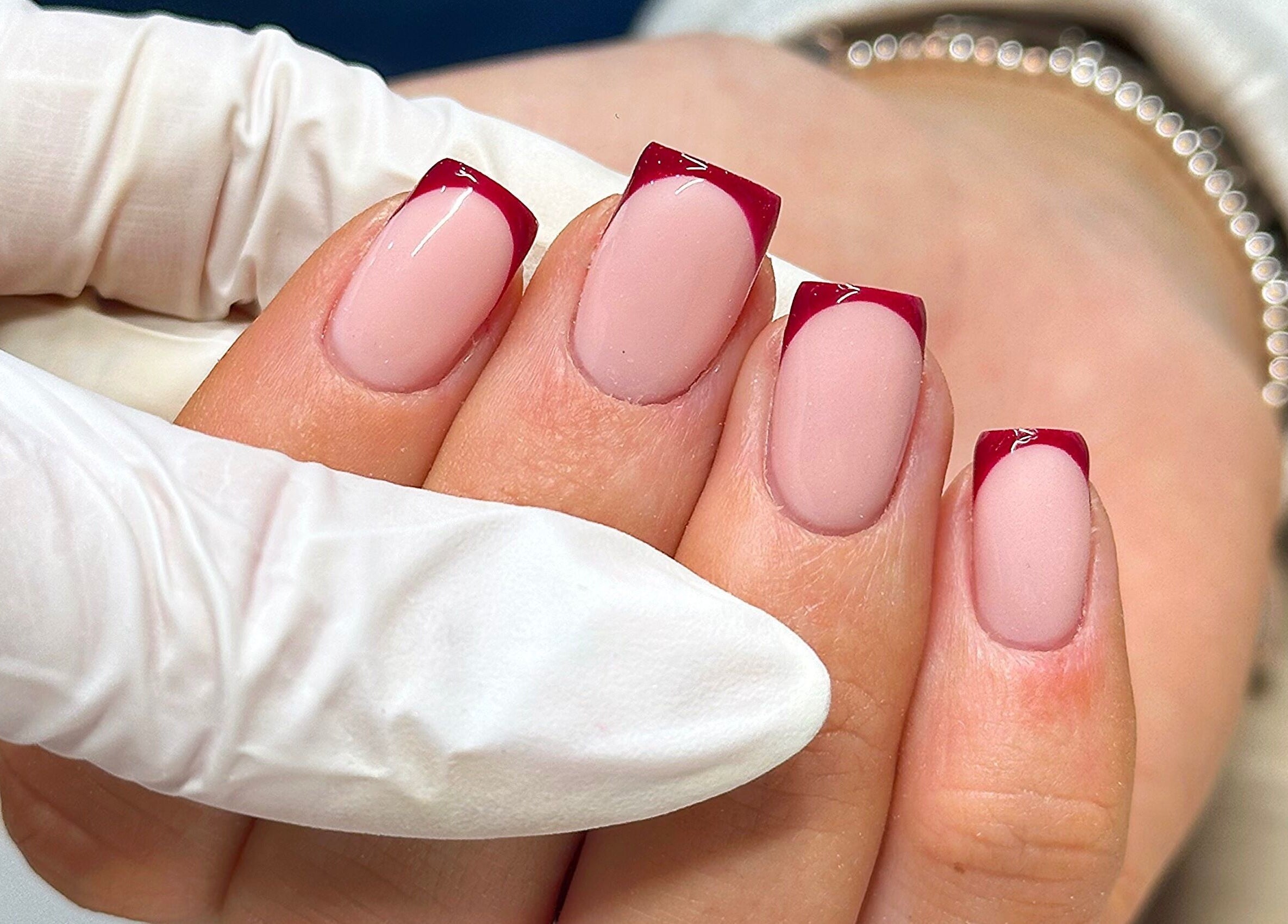 Close-up of elegant French manicure with red tips at Bydarcyella, Birmingham, England, GB.