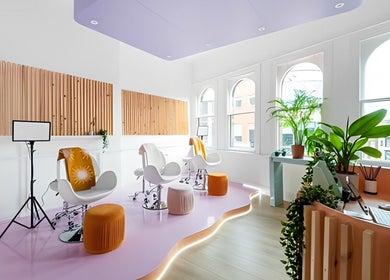 Bright salon interior at The Glow Up Social, Manchester, England, GB, with stylish chairs and greenery.