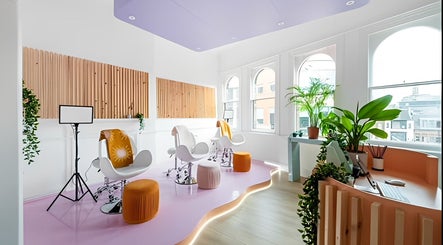 Bright salon interior at The Glow Up Social, Manchester, England, GB, with stylish chairs and greenery.