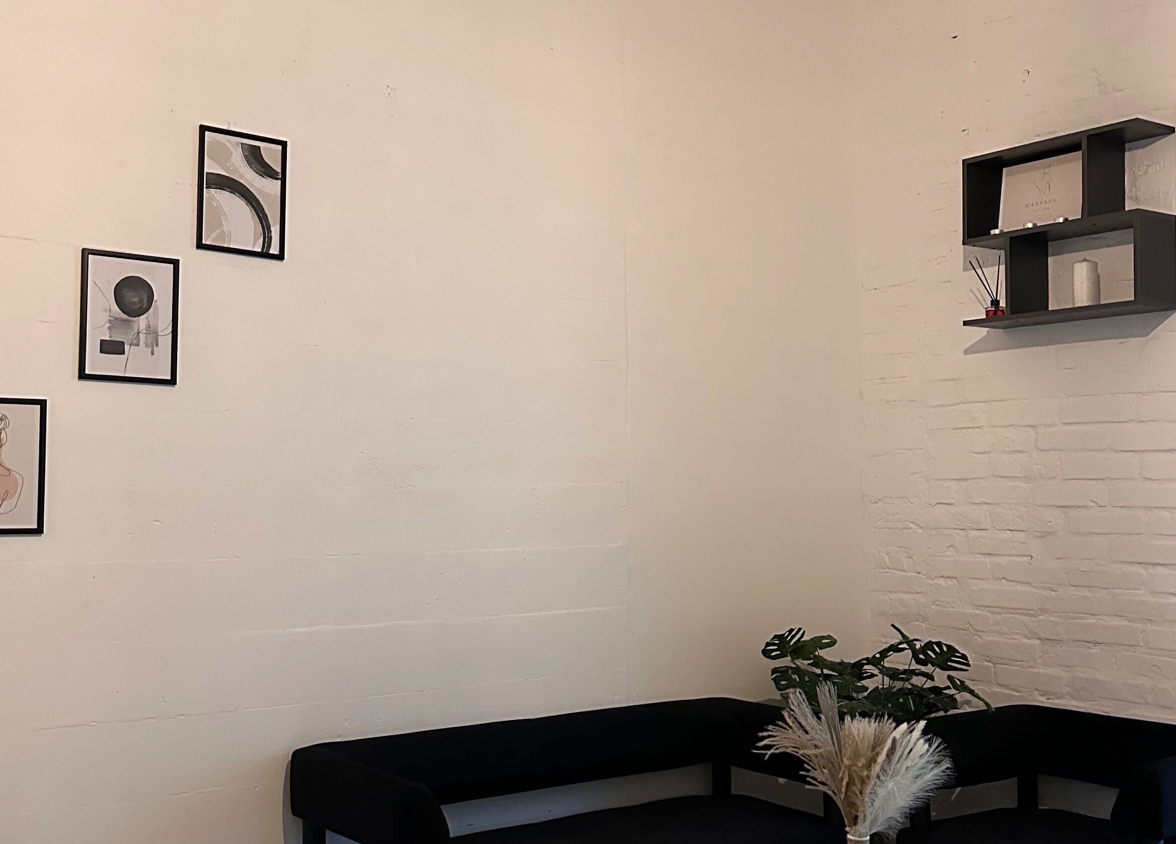 Затишний куточок в “Saba” massage studio, Київ, UA з чорним диваном і картинами на стіні.