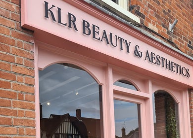 Charming pink storefront of Rhiannon's Beauty Box, Long Melford, England, GB against a brick facade.