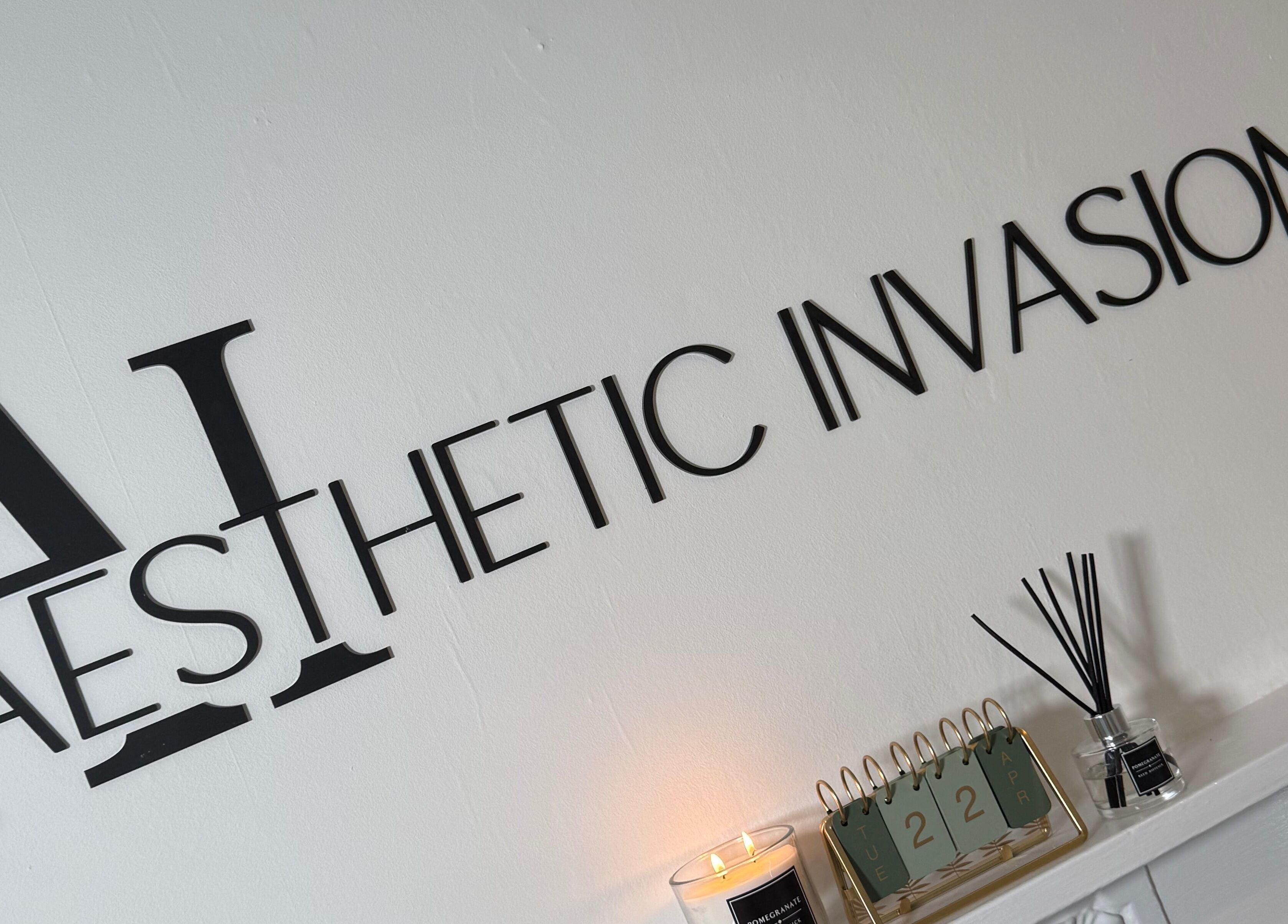 Elegant Aesthetic Invasion logo on wall at Liverpool, England, GB venue with candle and reed diffuser.