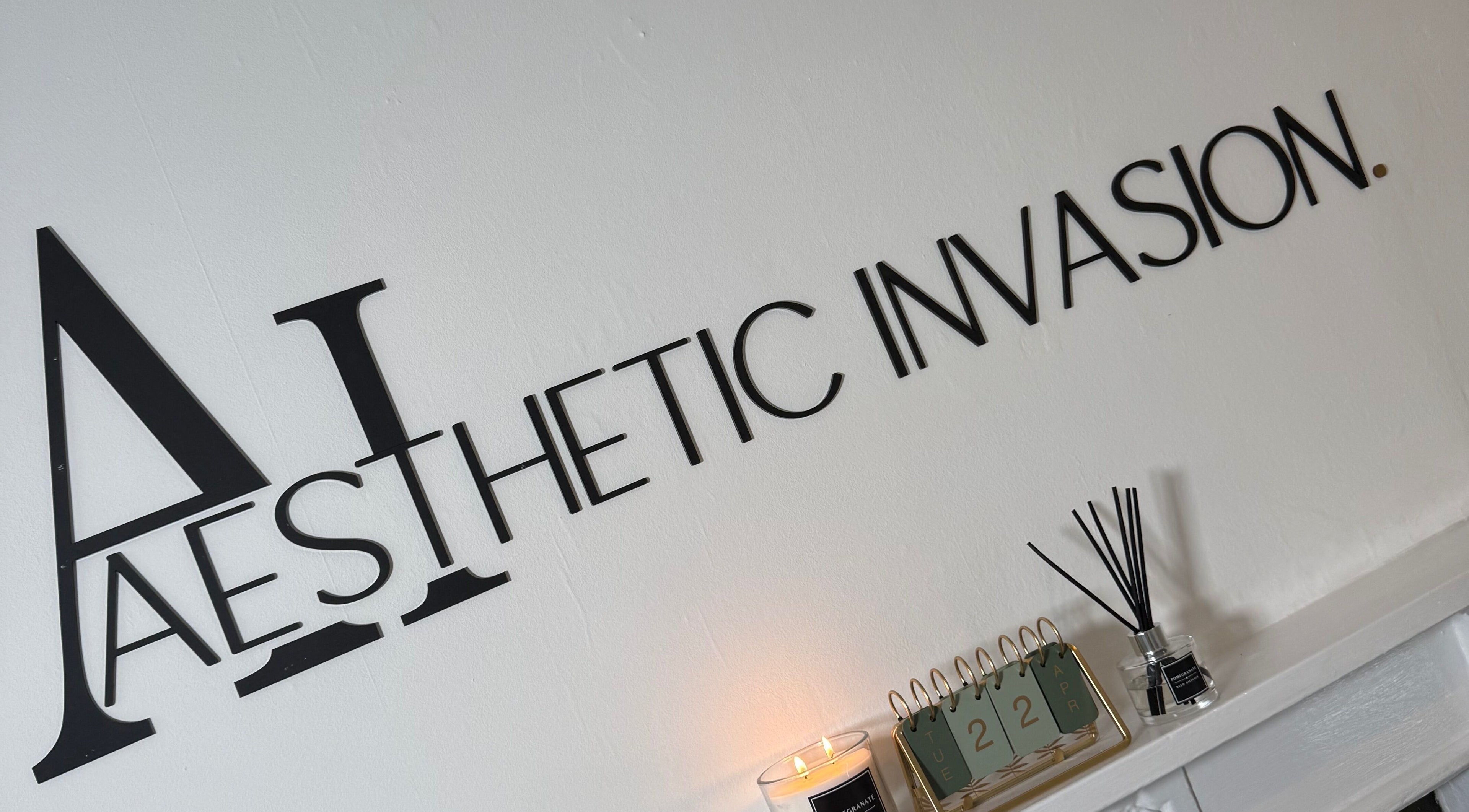 Elegant Aesthetic Invasion logo on wall at Liverpool, England, GB venue with candle and reed diffuser.