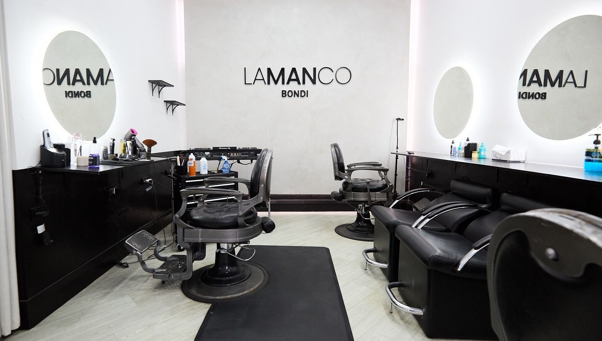 Modern interior of Lamanco Barbershop at Bondi Beach, New South Wales, AU, featuring sleek chairs and mirrors.