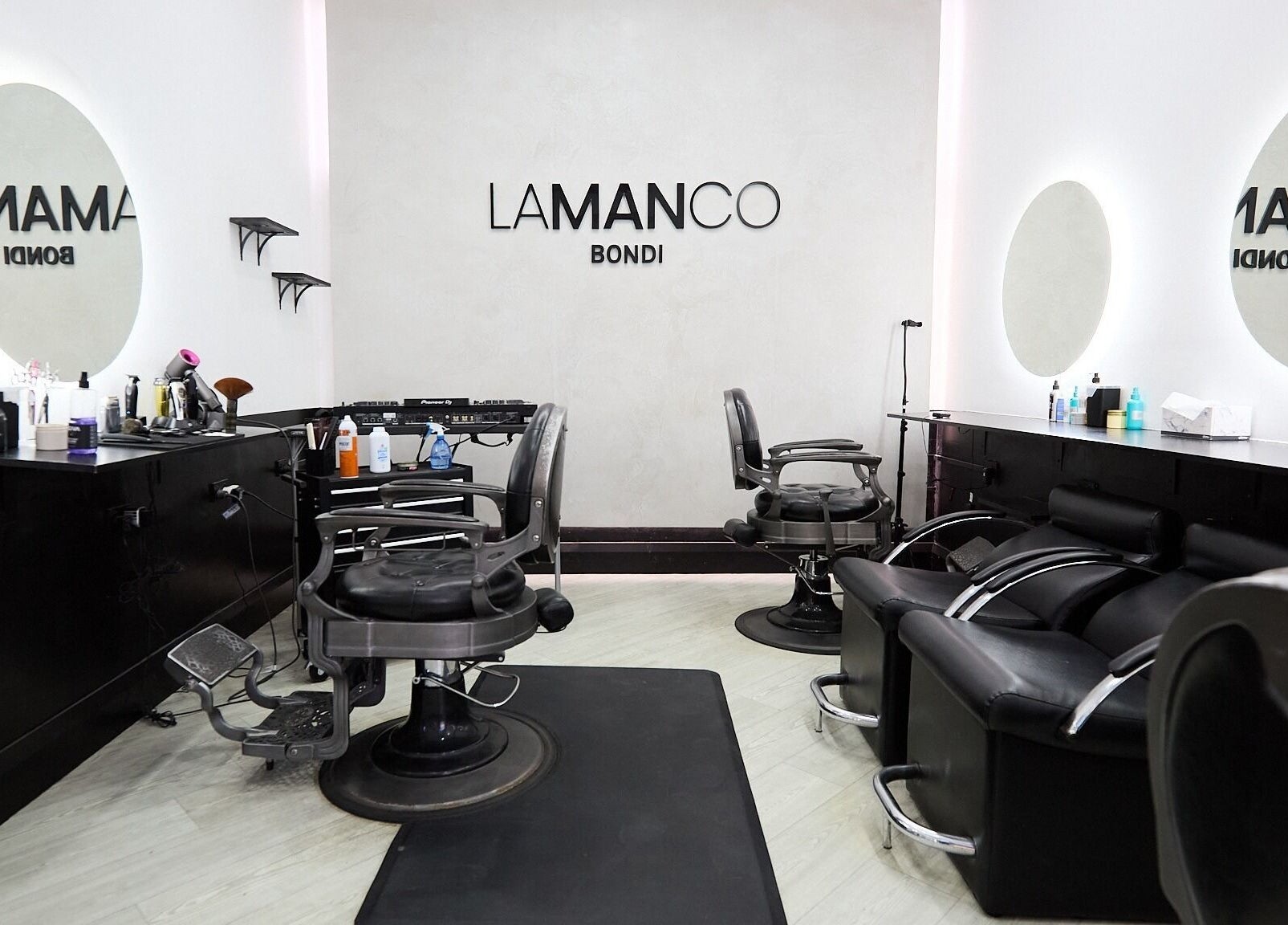 Modern interior of Lamanco Barbershop at Bondi Beach, New South Wales, AU, featuring sleek chairs and mirrors.