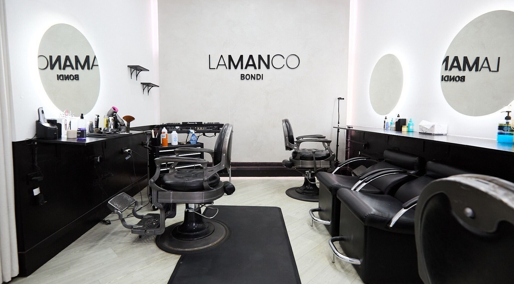 Modern interior of Lamanco Barbershop at Bondi Beach, New South Wales, AU, featuring sleek chairs and mirrors.