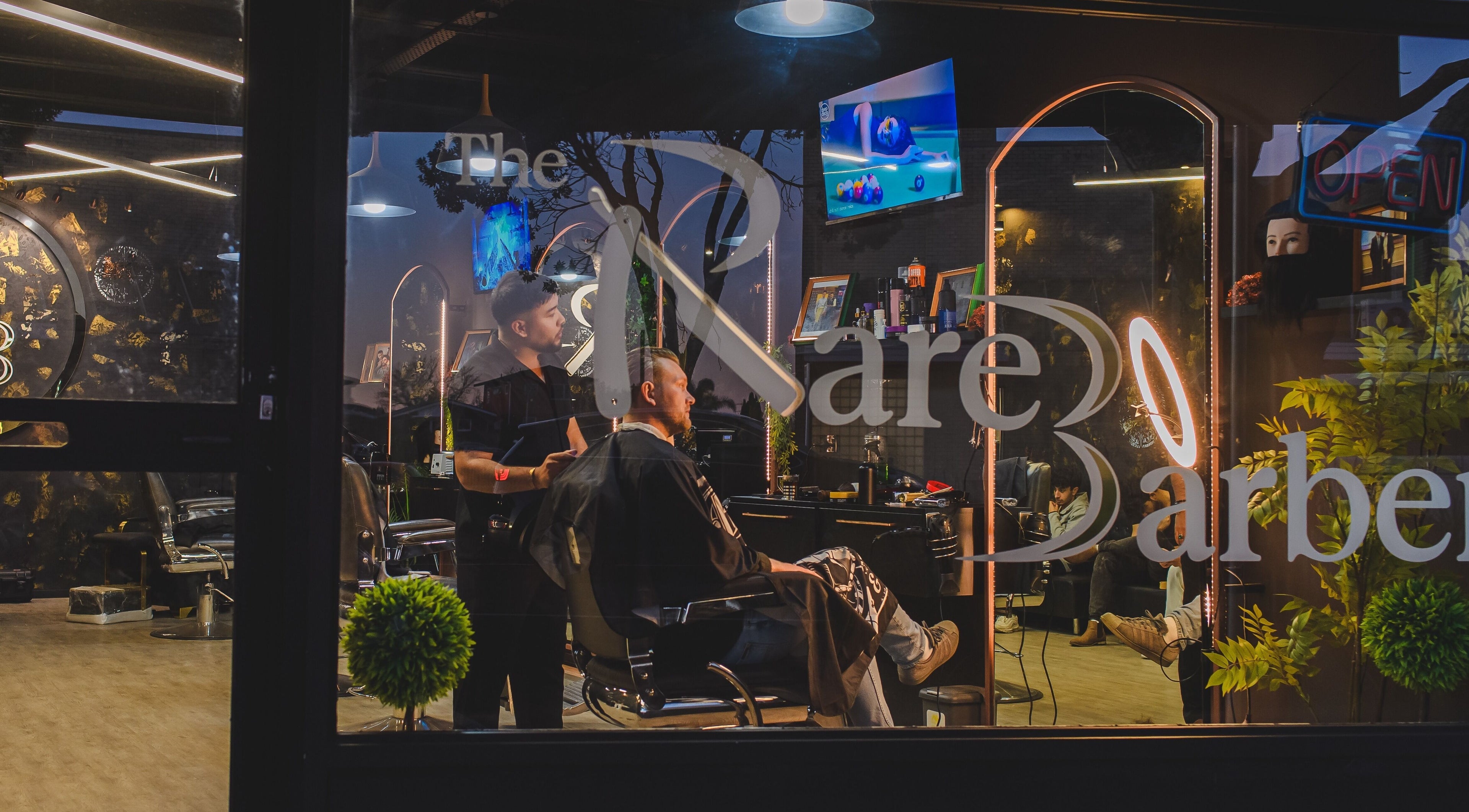 Inside view of The Rare Barber Shop, Auckland, NZ showing stylish interior and customer in chair.
