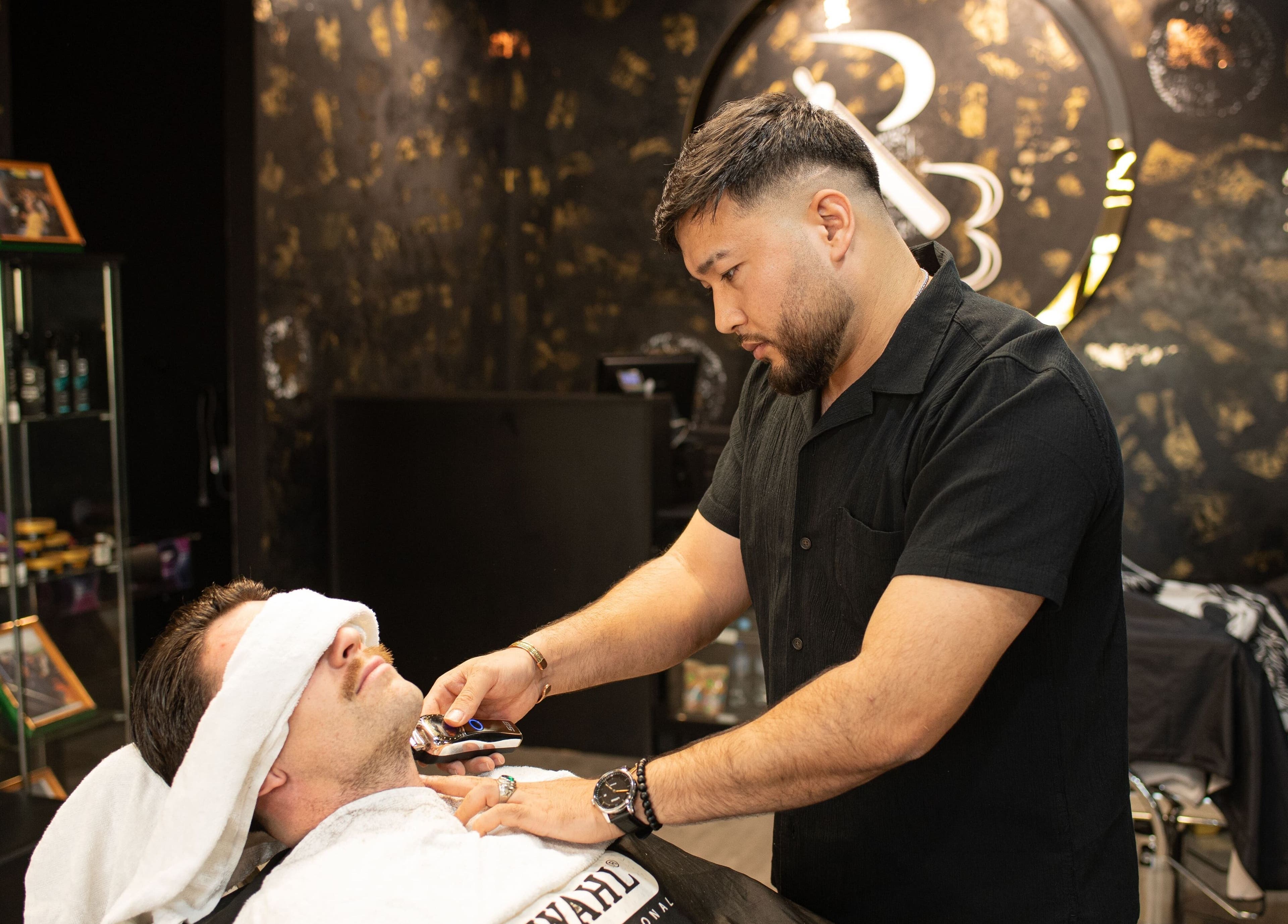 Barber shaving customer at The Rare Barber Shop, Auckland, Auckland, NZ. Luxurious interior showcases skill.