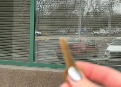 Hand holding a key reflecting in the window of Flutter + Frame Co. in Highland, Indiana, US.