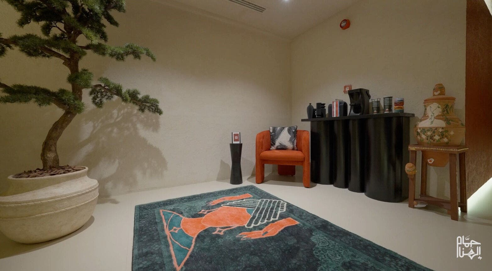 ديكور داخلي أنيق في حمام الهنا، الرياض، يضم كرسي برتقالي وسجاد ملون.