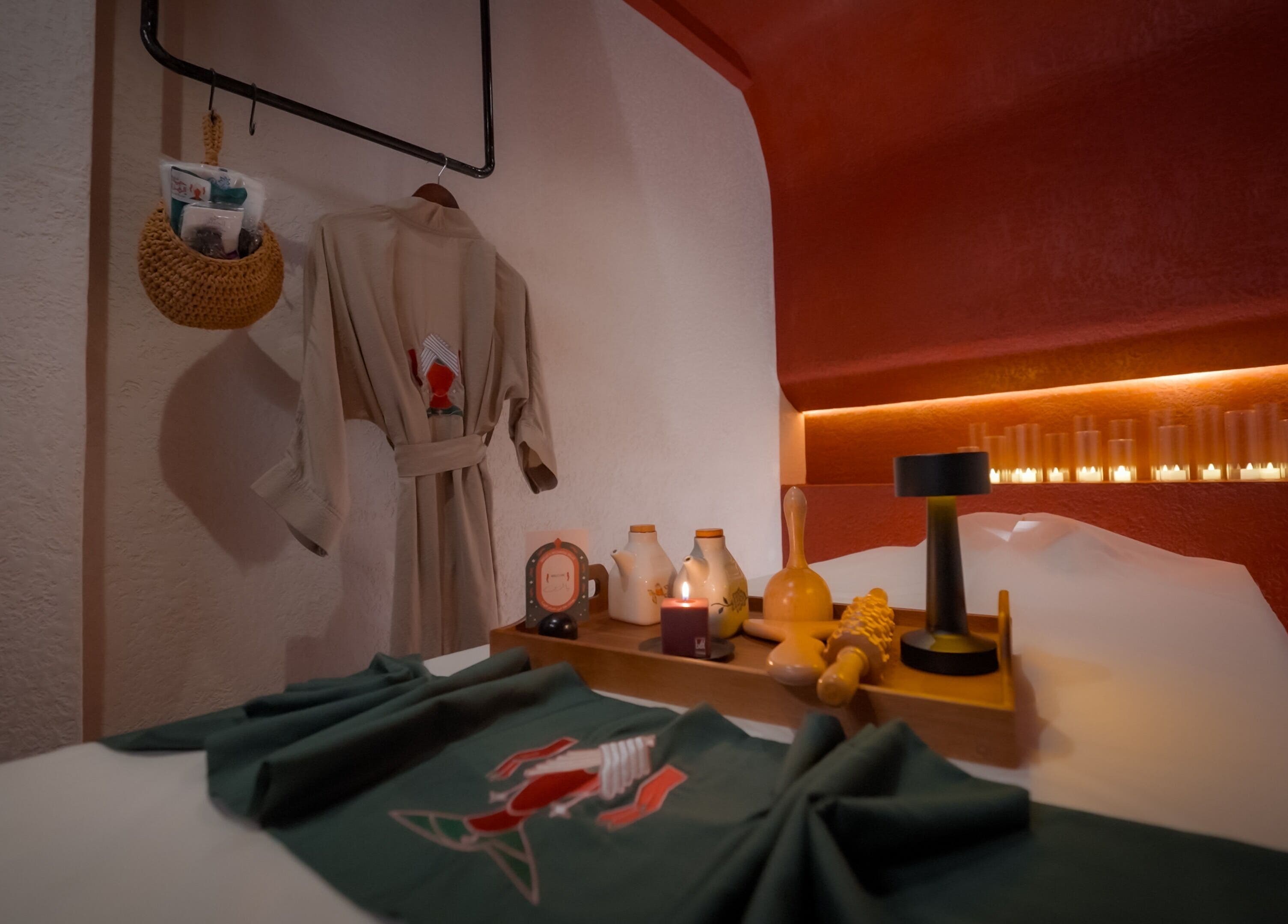 غرفة استرخاء في حمام الهنا بالرياض تتضمن رداء وحمام مضاء بالشموع.