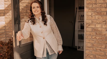 Stylist bij de ingang van Your HairStory in Winssen, Gelderland, NL. Klaar om klanten te ontvangen.