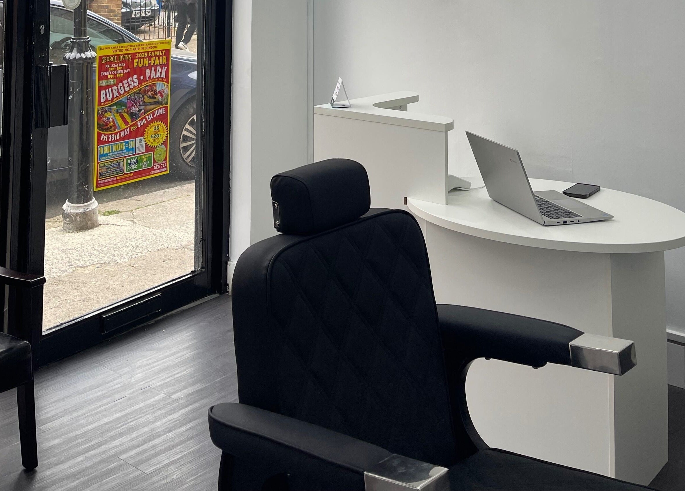 Sleek reception area at Alexandre Cuts, London, England, GB with barber chair and laptop on desk.