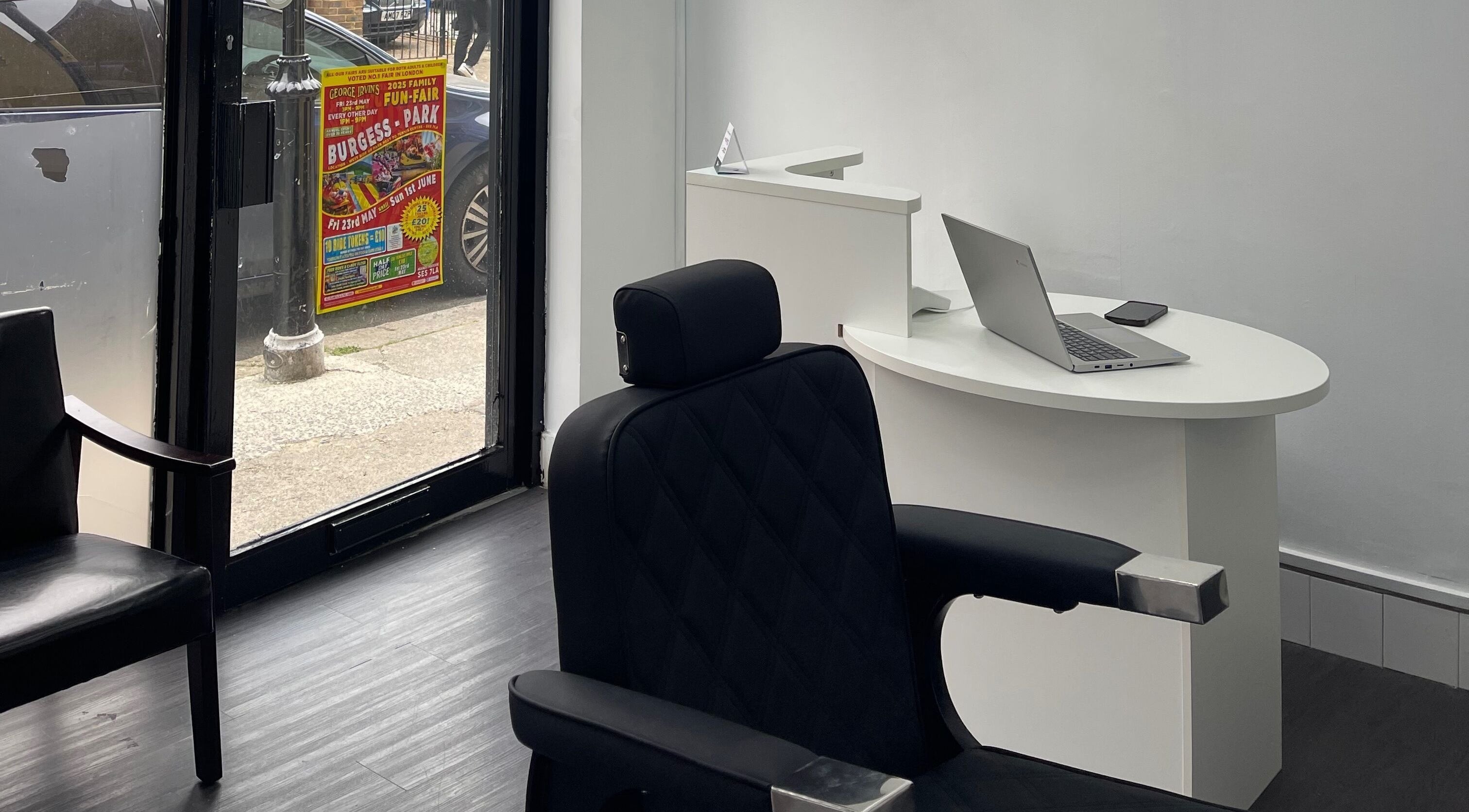 Sleek reception area at Alexandre Cuts, London, England, GB with barber chair and laptop on desk.