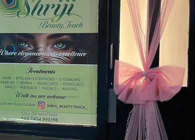 Entrance of Shriji Beauty Touch in Huddersfield, England, GB adorned with sign and pink decor.