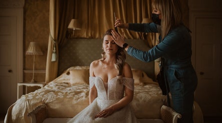 Bridal hairstyling at Emma Combe Hair in North Berwick, Scotland, GB. Elegant bride on bed with stylist.