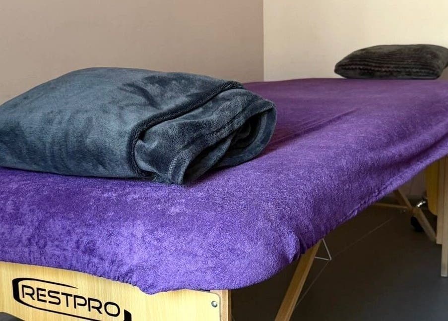 Massage table with purple cover at Energoterapija, Rīga, LV, offering relaxation and wellness.