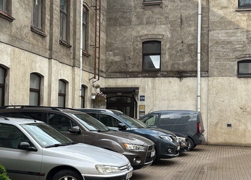 Exterior view of Energoterapija venue in Rīga, LV, featuring cars parked in a rustic courtyard.