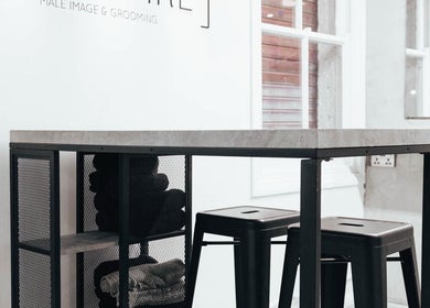 Industrial-style waiting area at Menspire St Albans, St Albans, England, GB with stools and table.