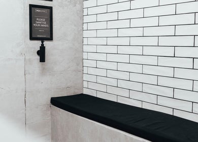 Modern sanitary area at Menspire St Albans, St Albans, England, GB with tiled wall and sanitizer.