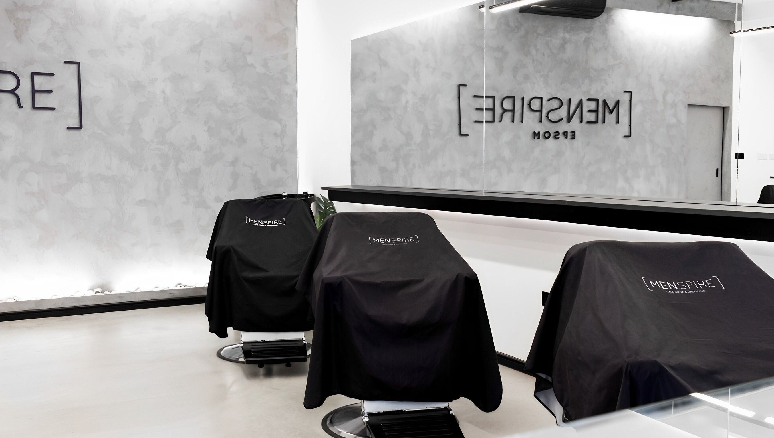 Sleek barber chairs in Menspire Epsom salon, Epsom, England, GB, featuring modern minimalist design.