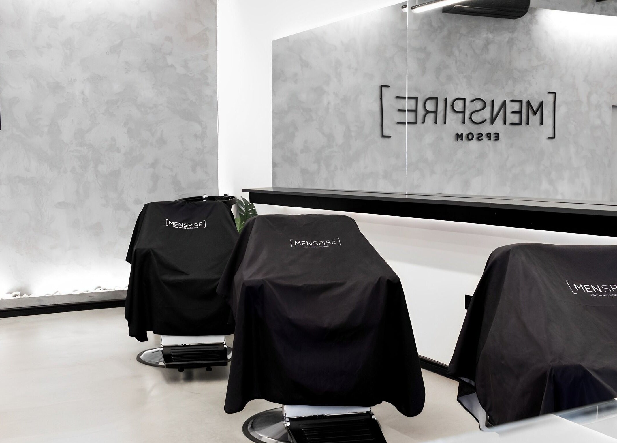 Sleek barber chairs in Menspire Epsom salon, Epsom, England, GB, featuring modern minimalist design.