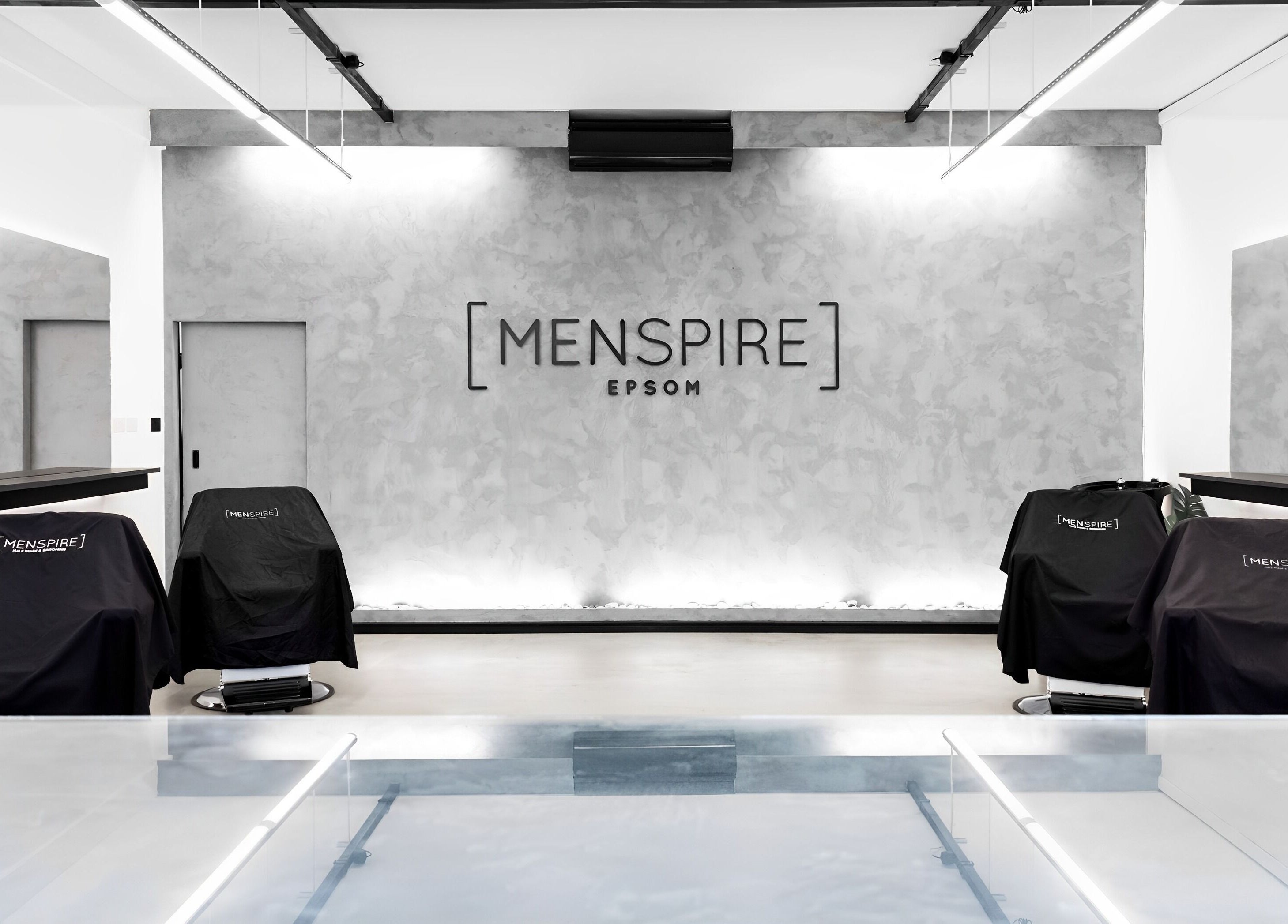 Modern interior of Menspire Epsom salon in Epsom, England, GB showcasing sleek design and barber chairs.