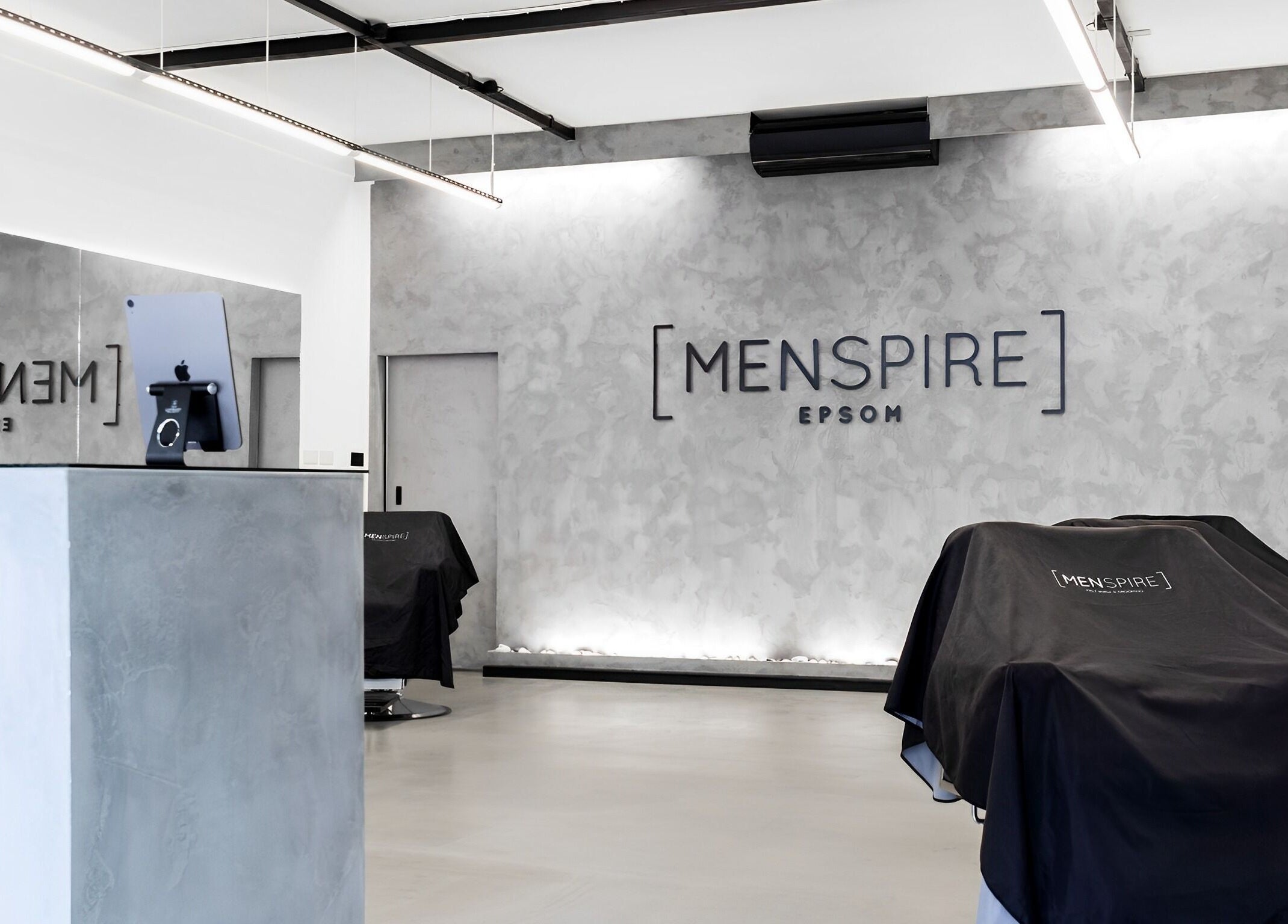 Modern interior of Menspire Epsom salon in Epsom, England, GB showcasing stylish minimalist decor.