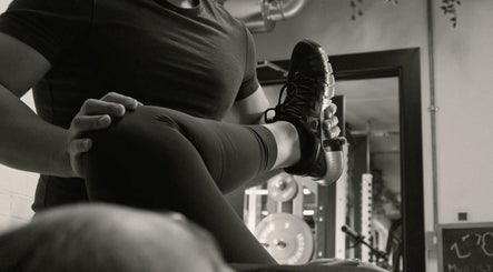 Personal trainer assists client with leg stretch at A Fitness - Health and Wellness Clinic, London, England, GB.