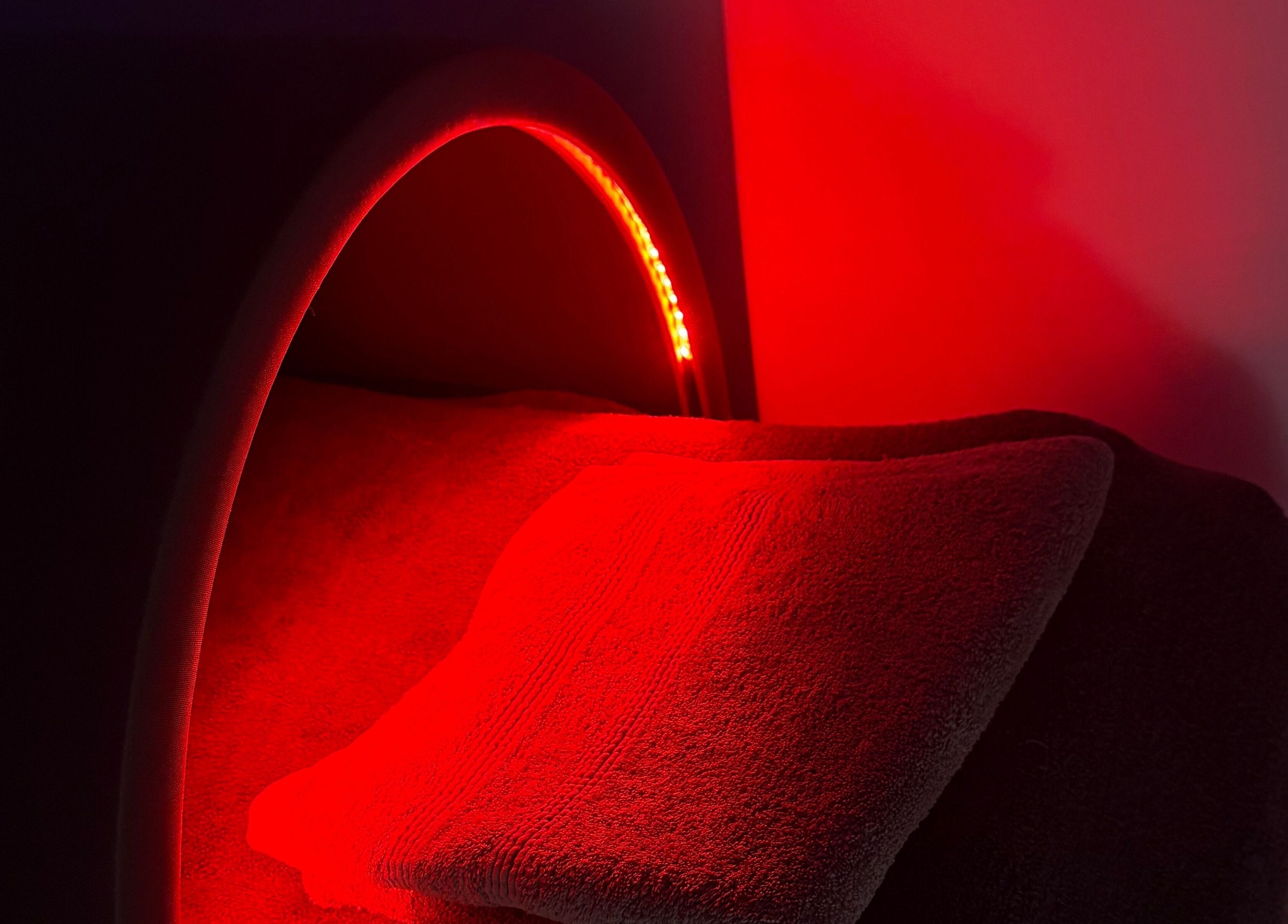 Infrared therapy bed at Solais Wellness, Dunblane, Scotland, GB, with soft towels under red lights.